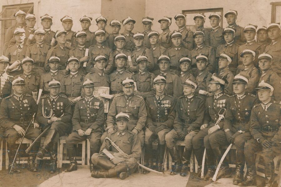 Zakończenie nauki w szkole podoficerskiej w 5. pułku strzelców konnych. W pierwszym rzędzie kadra oficerska pułku, powyżej strzelcy konni ze świadectwami ukończenia szkoły podoficerskiej oraz „Zarysami historji wojennej 5 pułku strzelców konnych” w rękach. Ludwik Kawik stoi trzeci z prawej w drugim rzędzie od dołu. Fot. archiwum rodzinne